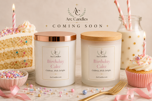 Two Arc Candles 'Birthday Cake' soy candles in white jars with rose gold and wood lids, displayed on a marble surface with cake, cupcake, sprinkles, and a glass bottle of milk in a celebratory setup. A 'COMING SOON' banner is overlaid at the top.