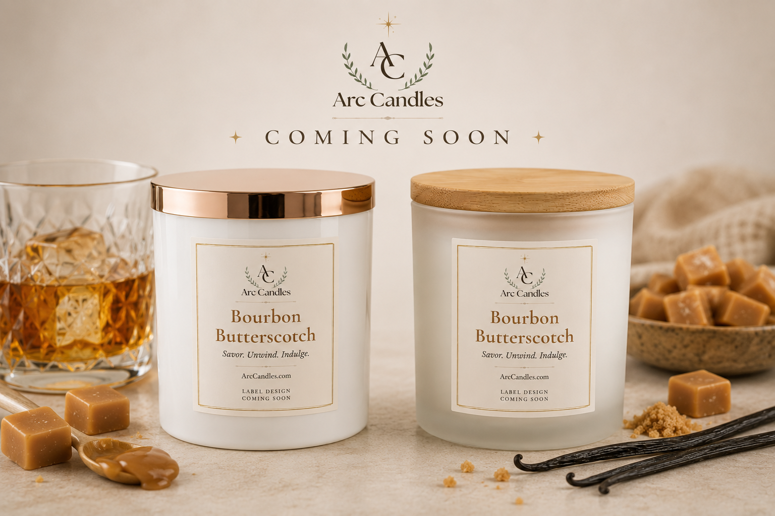 Two Arc Candle 'Bourbon Butterscotch' scented candles are displayed on a light beige surface with caramel pieces, vanilla beans, and a glass of whiskey. The left candle has a rose gold lid, and the right candle has a natural wood lid.