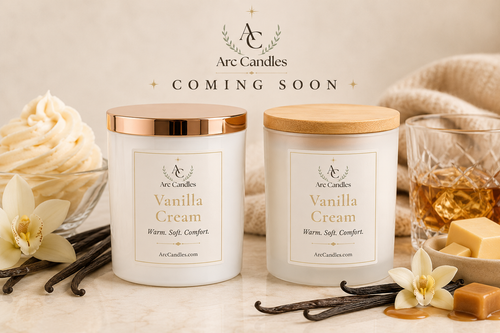 Two Arc Candles Vanilla Cream scented candles with white labels and lids in gold and wood finishes, displayed on a marble surface with vanilla flowers, vanilla beans, a glass of whiskey, and butter. The text 'Arc Candles COMING SOON' is overlaid at the top.